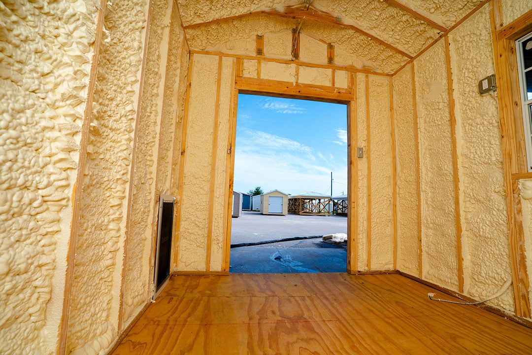 Finished spray foam interior of a shed showing insulated walls and open door